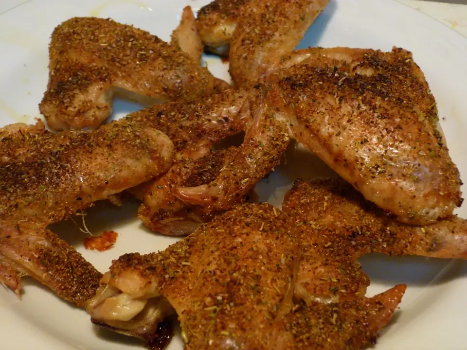 Alitas de pollo enteras doradas y condimentadas, servidas en un plato