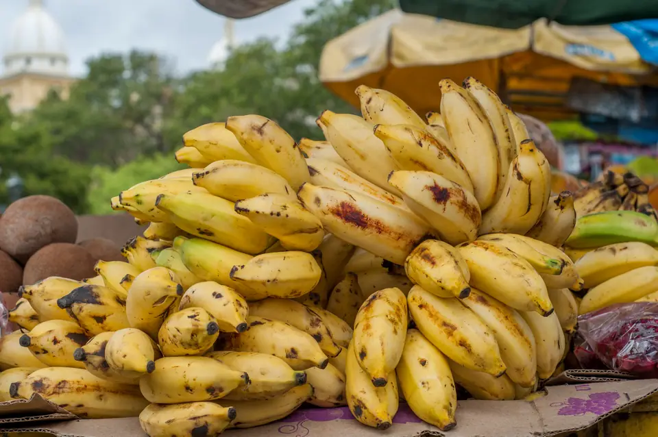 Racimos de bananas maduras apilados en un puesto de mercado