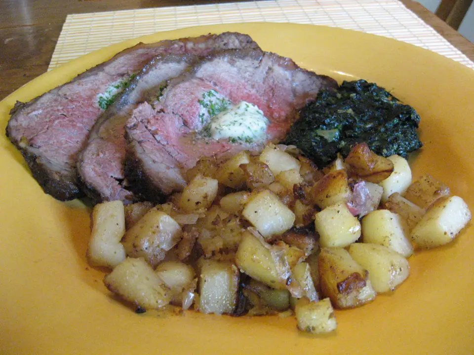 Bife cortado en fetas con el interior rosado, con manteca de hierbas, papas salteadas y espinaca