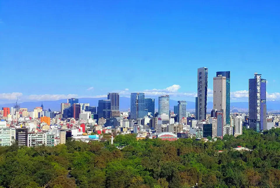 Rascacielos de Paseo de la Reforma en Ciudad de México sobre el verde de un bosque, con cielo despejado