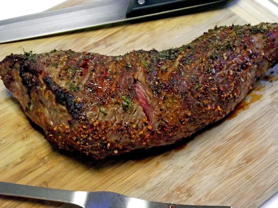 Colita de cuadril entera asada, con costra de especias, sobre una tabla de madera