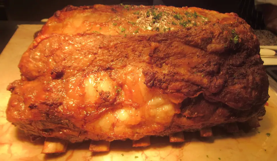 Costillar de res asado entero, con la superficie dorada y las puntas de los huesos a la vista