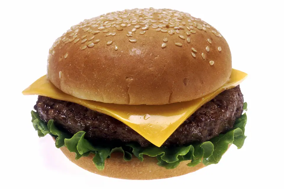 Hamburguesa con queso, lechuga y pan con sésamo sobre fondo blanco