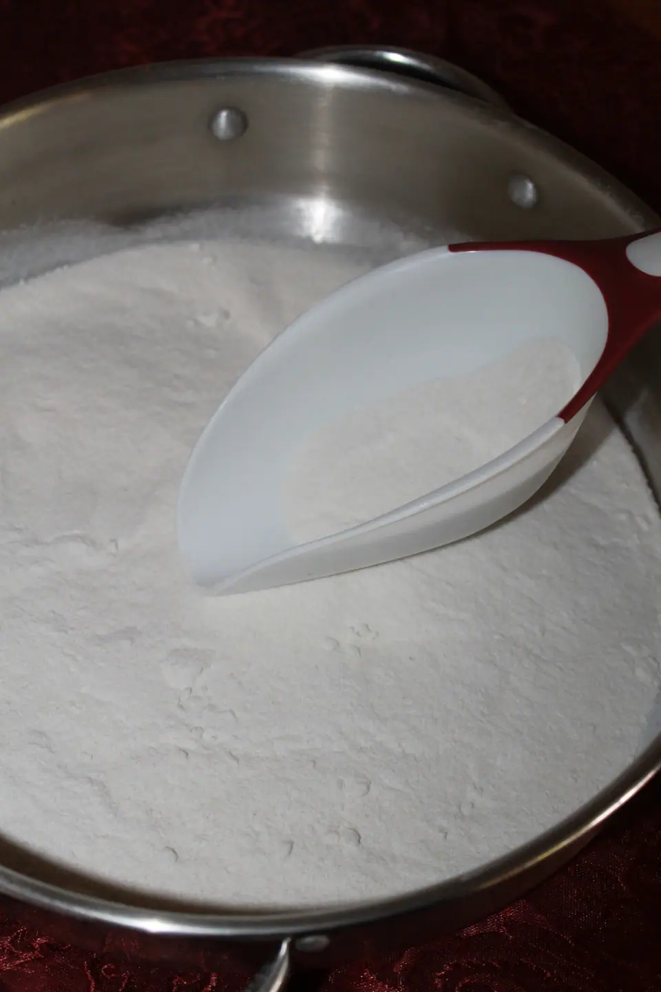 Harina de arroz blanca en un recipiente de acero con una pala de plástico