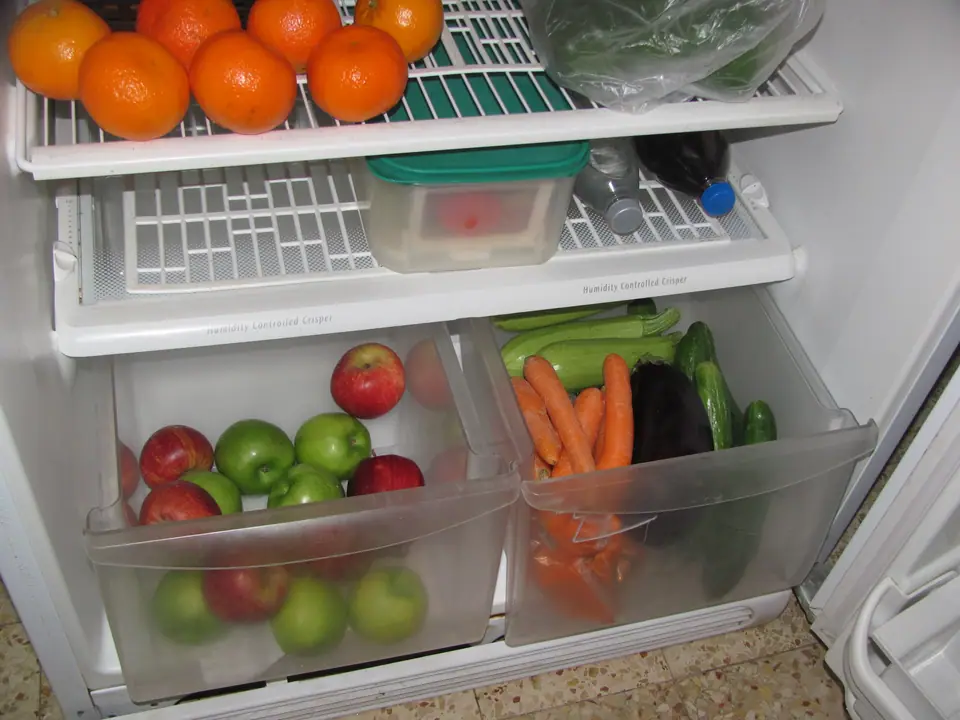 Cajones de verdura de una heladera con manzanas, zanahorias y otras verduras
