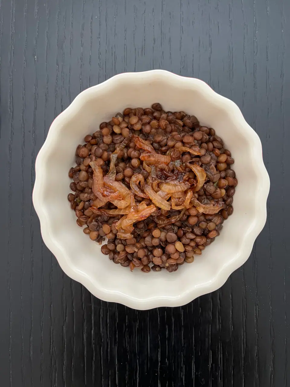 Bol blanco con lentejas cocidas y cebolla caramelizada por encima