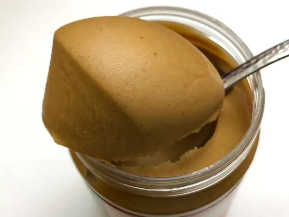 Cucharada de mantequilla de maní cremosa sobre un frasco abierto