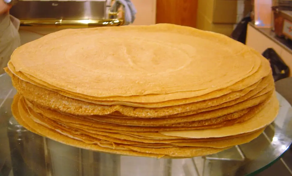 Pila de panqueques finos y dorados sobre una bandeja
