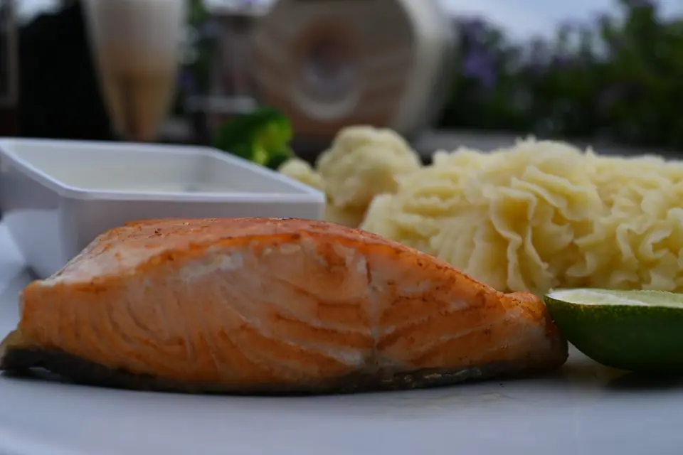 Filete de salmón sellado en sartén, servido con puré de papas y una rodaja de lima