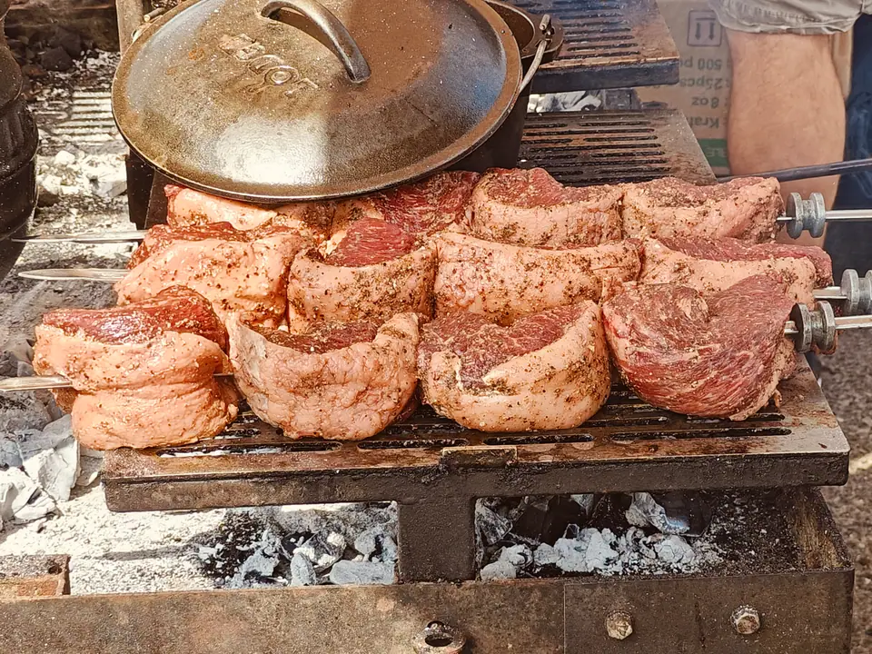 Trozos de picaña doblados en espadas, con su capa de grasa, sobre brasas de carbón
