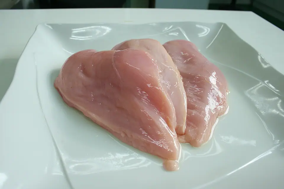 Pechugas de pollo crudas en un plato blanco