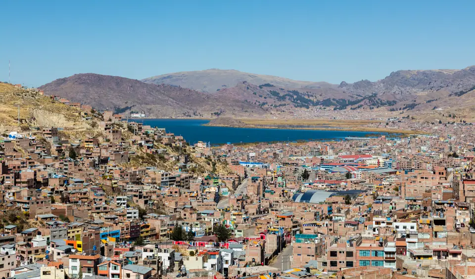Vista de la ciudad de Puno sobre las laderas, con el lago Titicaca y montañas al fondo