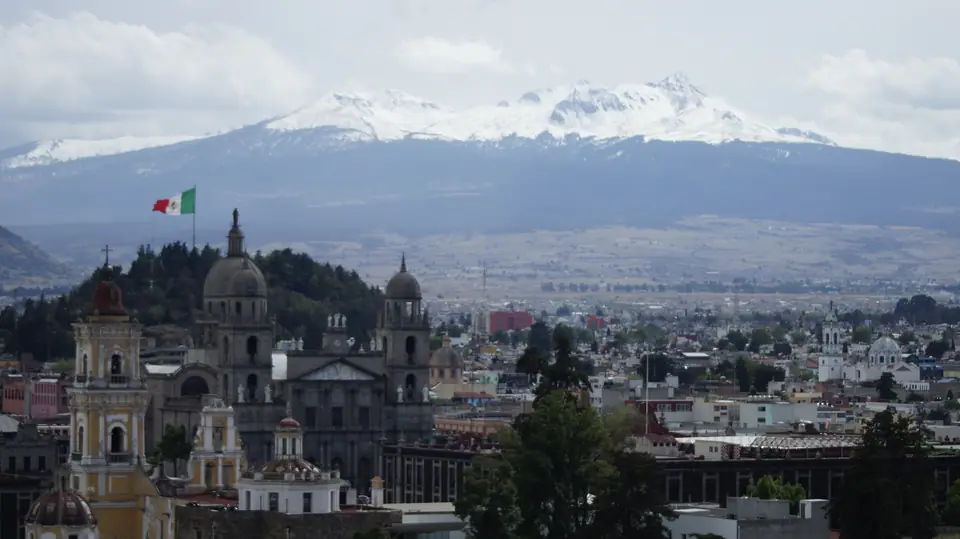 Vista de la ciudad de Toluca con cúpulas de iglesias y un volcán nevado al fondo